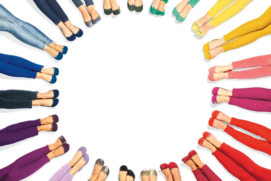 women with different color pants and shoes lay in circle to create a color wheel